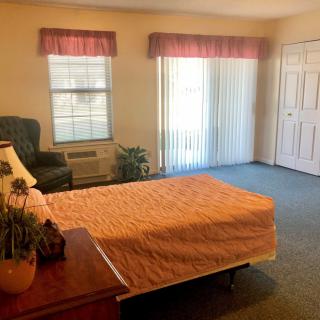 A cozy bedroom with a bed, chair, and windows adorned with curtains.