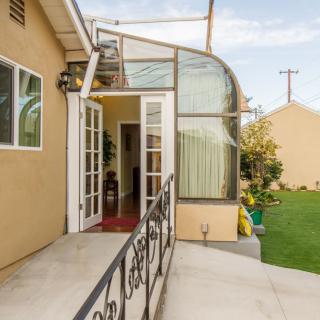 A house with a patio, featuring a glass-enclosed sunroom and garden area.