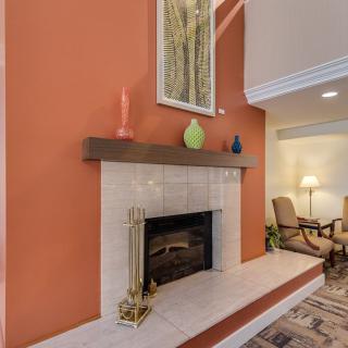 A cozy living room with an orange accent wall featuring a fireplace, decorative vases, and artwork.