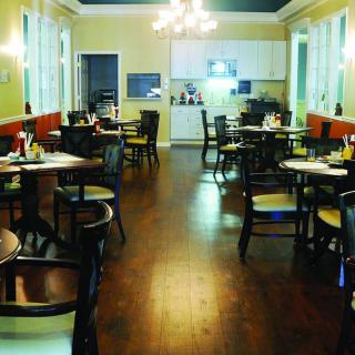A cozy restaurant interior with neatly arranged tables and chairs under a chandelier.