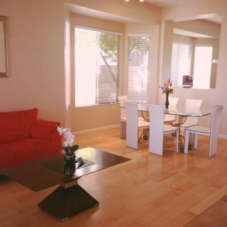 A modern living and dining space with a red sofa, sleek coffee table, and a glass-top dining set on a hardwood floor.