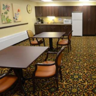 A cozy dining area with tables and chairs, adjacent to a kitchenette equipped with a refrigerator and microwave.
