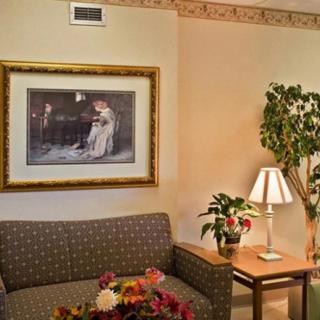 A cozy living room corner with a sofa, painting, lamp, indoor plant, and decorative elements.