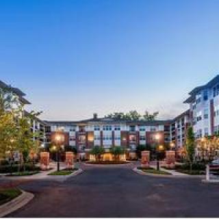 A modern apartment complex with well-maintained landscaping and an inviting entrance during the evening.