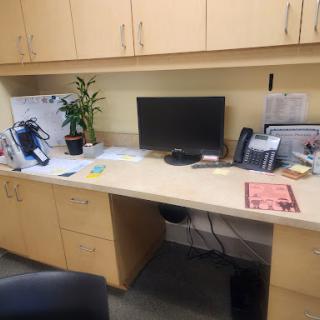 A neatly organized office desk featuring a computer, phone, and a small potted plant.