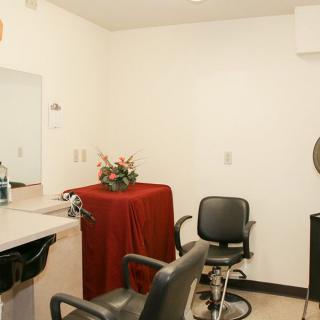 An interior view of a barbershop with chairs, a mirror, and decorative flowers.