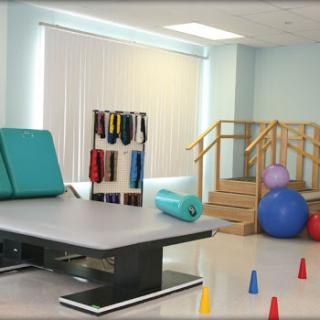 A well-equipped physical therapy room featuring exercise mats, resistance bands, balance balls, and a staircase for rehabilitation exercises.