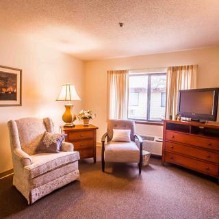 A cozy living room with two armchairs, a lamp, and a television near the window.