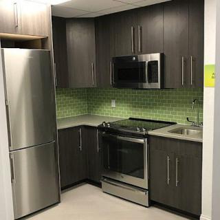 A modern kitchen featuring stainless steel appliances and a green tiled backsplash.
