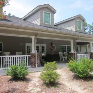 A charming house with a spacious porch and neatly landscaped front yard.