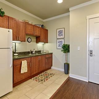 A modern apartment kitchen with wooden cabinets, a refrigerator, and decorative elements.