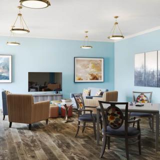 A modern and cozy living room with blue walls, featuring comfortable seating, a television, and decorative artwork.