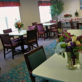 A cozy dining area with tables and chairs adorned with flower arrangements.