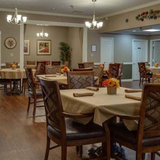 A cozy dining room with neatly arranged tables and chairs, featuring warm lighting and tasteful decor.