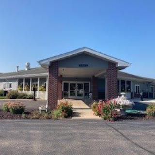 A front view of a building entrance surrounded by landscaped flowers.