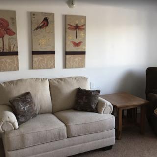 A cozy living room with a beige sofa and decorative wall art.
