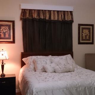 A cozy bedroom with a neatly made bed and warm lighting from a bedside lamp.