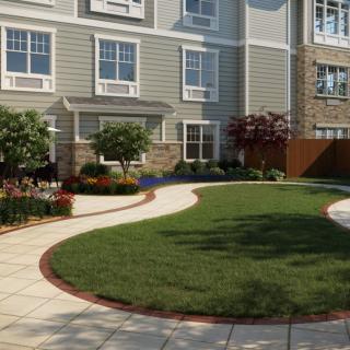 A well-maintained garden with a curved pathway and neatly trimmed lawn in front of a residential building.