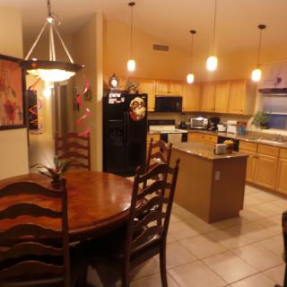 A modern kitchen with a connected dining area featuring wooden furniture and warm lighting.