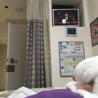 A patient resting in a hospital bed with a television mounted on the wall.