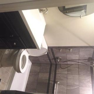 A modern bathroom with a toilet, sink, mirror, and shower area.