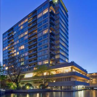 A modern skyscraper illuminated at night, reflecting in the surrounding water.