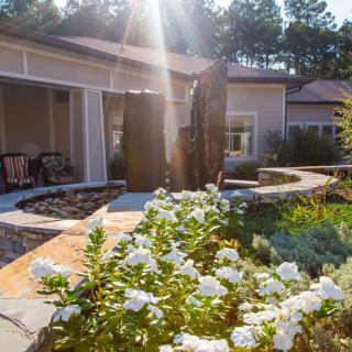 A sunlit garden with white flowers and a peaceful patio area.