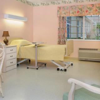 A clean and well-organized hospital room with a single bed and a window.