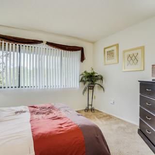 A cozy and well-decorated bedroom featuring a comfortable bed, stylish dresser, and a touch of greenery.