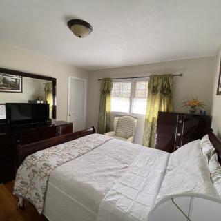 A cozy bedroom with a large bed, dresser, and window with curtains.