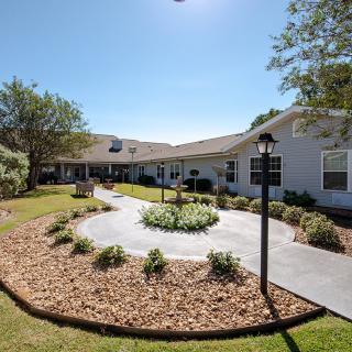 A well-maintained building with a landscaped garden and a winding pathway under a clear blue sky.