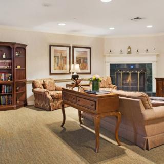 A cozy living room with a fireplace, sofas, and a wooden bookshelf.
