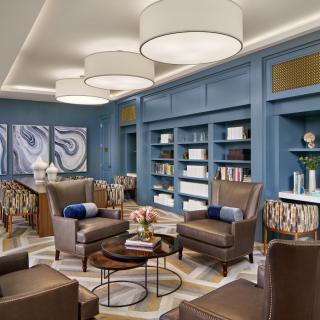 A modern lounge with blue walls, comfortable armchairs, and contemporary art pieces.