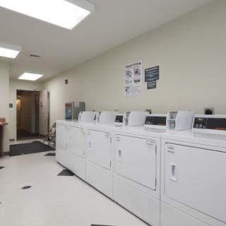 A clean and organized laundry room featuring multiple washing machines and dryers.