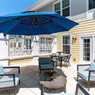A sunny patio featuring outdoor furniture and a large blue umbrella.