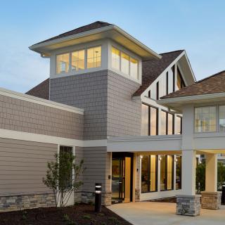 A modern residential building with large windows and a contemporary design, captured during the evening.