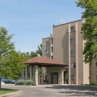 A hotel building with an entrance surrounded by trees and a driveway.