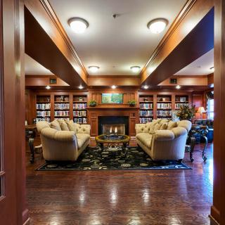 A luxurious library interior with comfortable seating and a cozy fireplace.