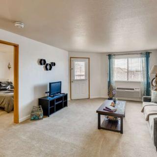 A cozy living room with a sofa, coffee table, and a television setup near a window.