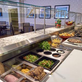 A self-service buffet featuring a variety of salads and dishes in a restaurant setting.