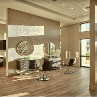 A modern salon interior featuring stylish chairs and large mirrors with a spacious layout and wooden flooring.