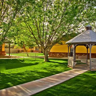 A scenic view of a park with a gazebo and pathway surrounded by lush greenery.