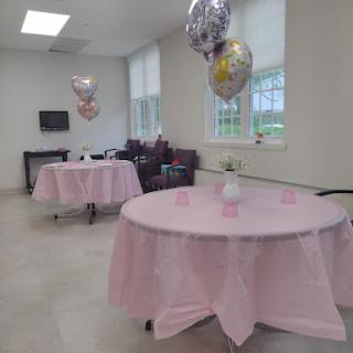 A beautifully decorated space for a celebration with pink tablecloths and balloons.