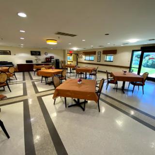 A spacious and well-lit dining area featuring neatly arranged tables and chairs, perfect for gatherings or meal service.
