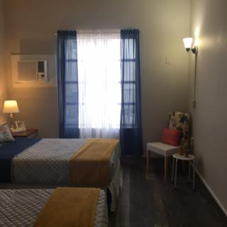 A cozy bedroom with two beds, illuminated by soft lighting and natural light through the window.