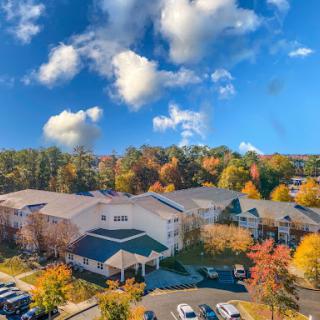 A picturesque autumn scene showcasing colorful trees surrounding a residential complex under a bright blue sky.