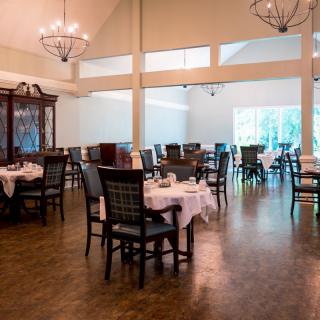 An elegant dining area with empty tables and chandeliers.