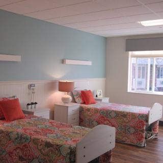 A hospital room with two neatly arranged beds and a window allowing natural light.