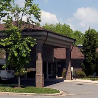 A view of a building entrance surrounded by greenery and blue skies.