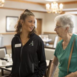 A young woman assisting an elderly woman in a community setting.